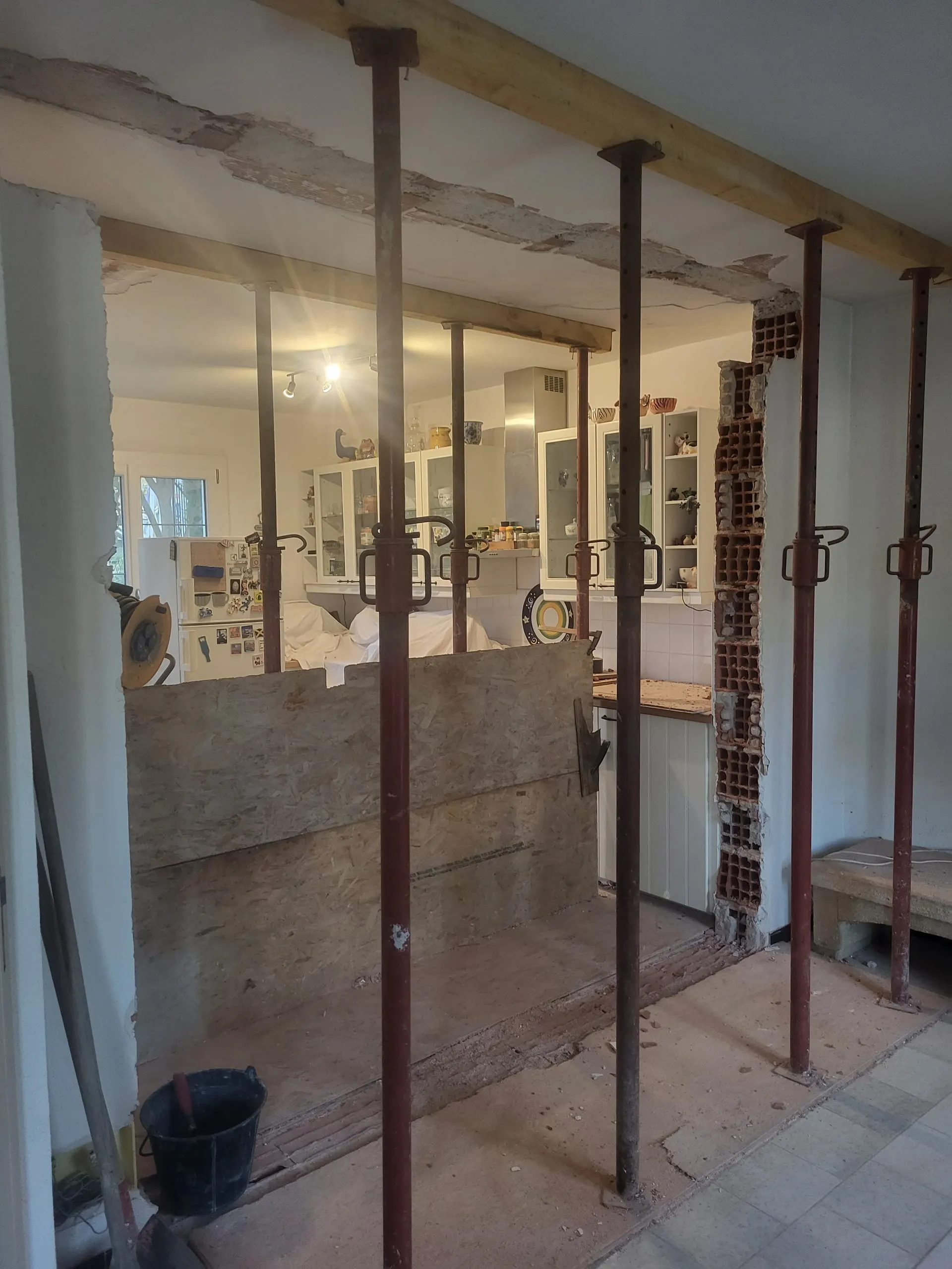 Ouverture d’un mur intérieur maintenue par des étais pendant des travaux de rénovation.