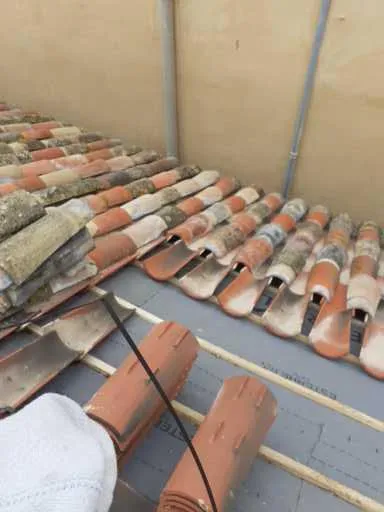 Tuiles canal déposées sur un écran de sous-toiture et des liteaux pendant une rénovation de couverture.