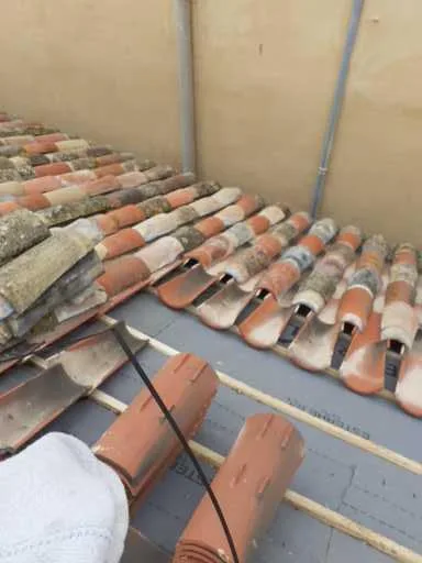 Tuiles canal déposées sur un écran de sous-toiture et des liteaux pendant une rénovation de couverture.