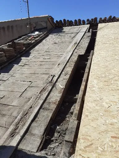 Pan de toiture découvert avec liteaux apparents et tuiles déposées pendant une rénovation.