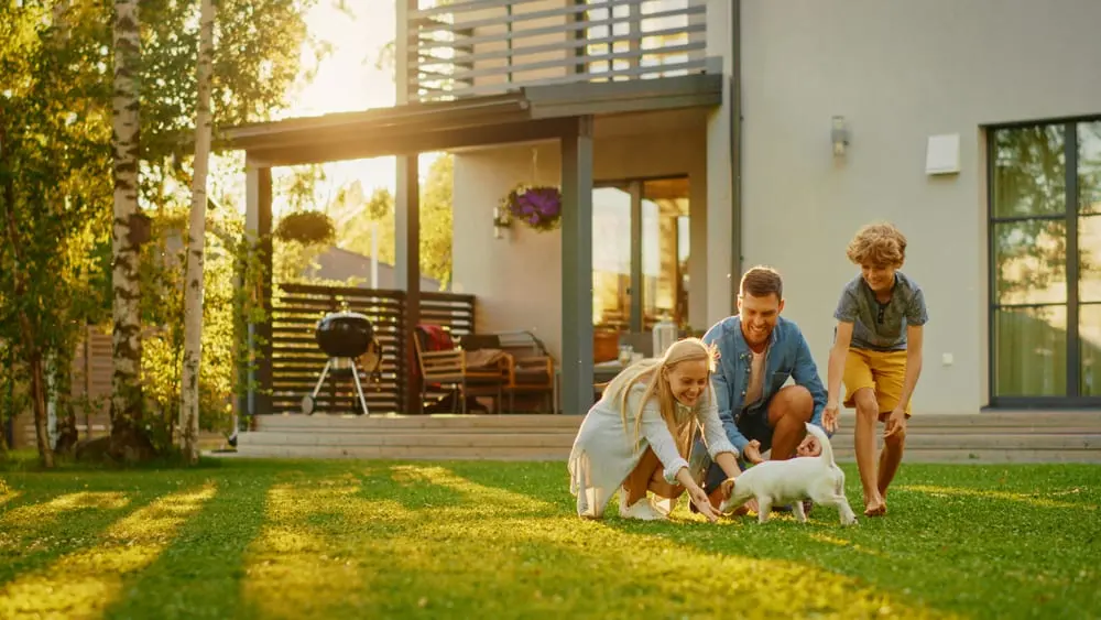 Famille réunie dans le jardin d’une maison contemporaine avec un chiot.