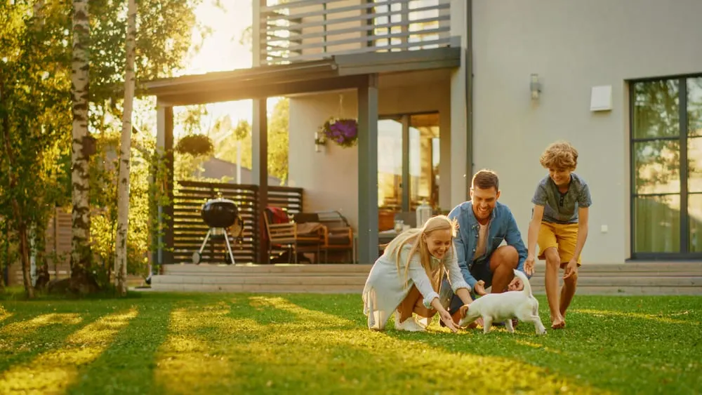Famille réunie dans le jardin d’une maison contemporaine avec un chiot.